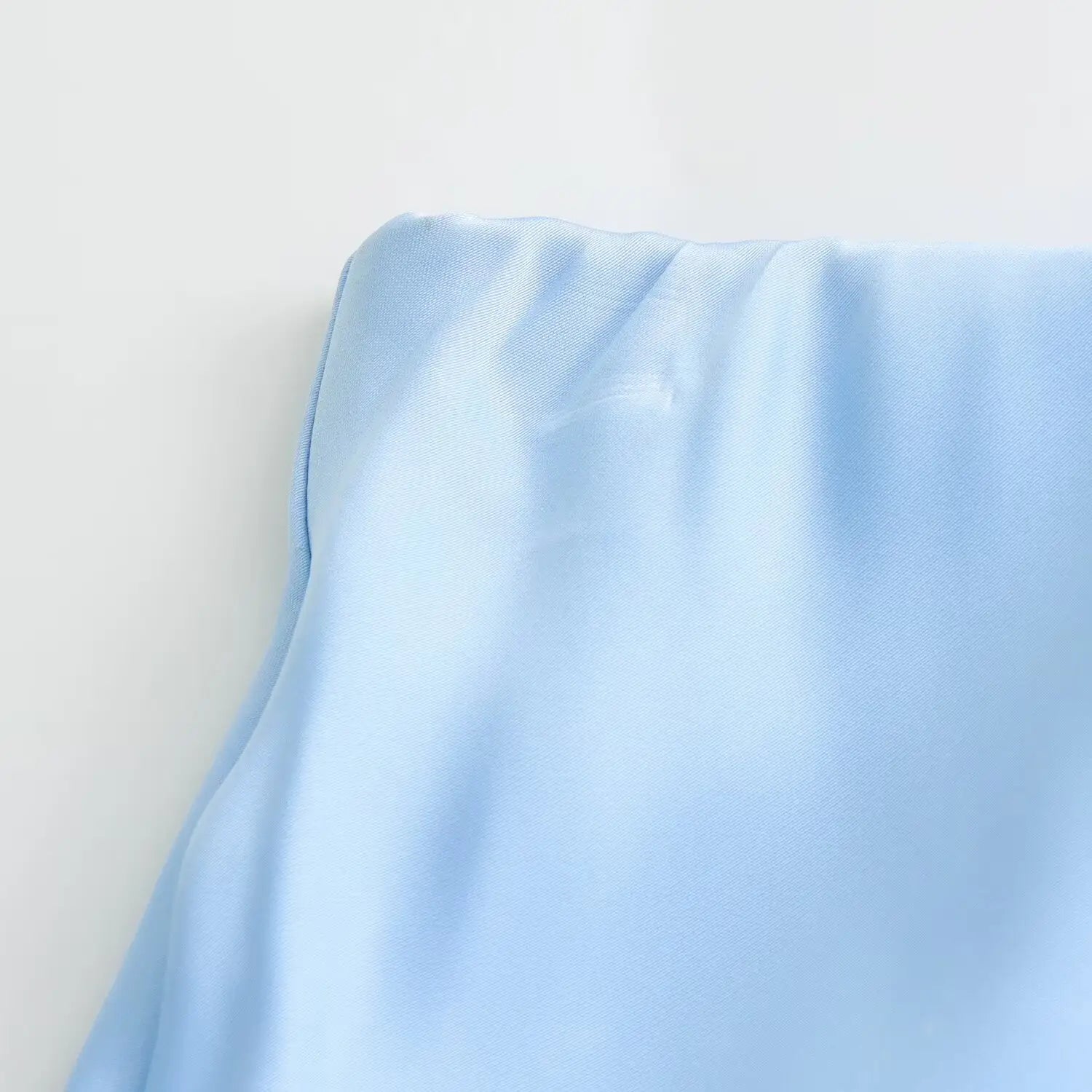 Une jupe midi en satin bleu clair tendre, à taille haute, surface réfléchissante lisse, conçue pour une tenue élégante.
