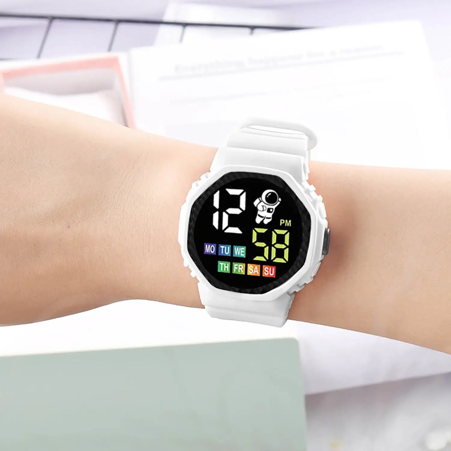 White kids waterproof led digital astronaut watch with black face and colorful led display showing time day of the week and astronaut icon on screen.