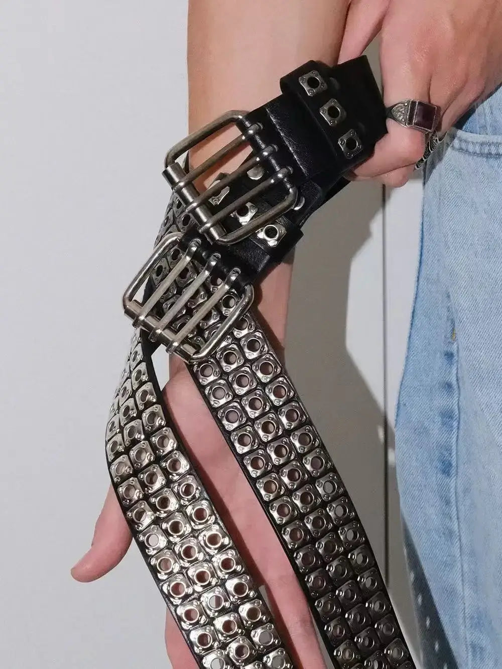 Black leather punk belt featuring multiple silver-toned buckles and rows of square metal studs.
