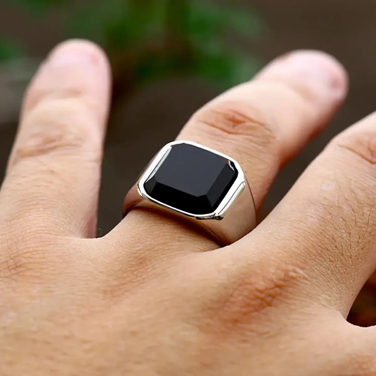 Ein eleganter schwarzer Onyx-Signetring in Silber für Damen und Herren, mit einem markanten quadratisch geschliffenen schwarzen Onyx-Stein, der in einem polierten Metallband eingesetzt ist.