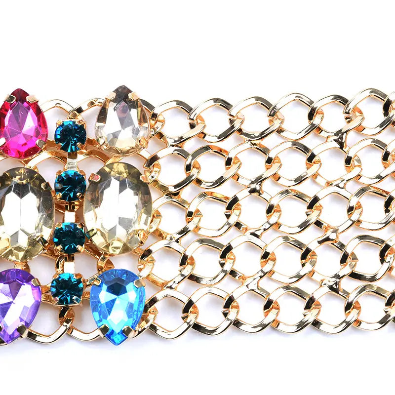 Un collier ras du cou en cristal arc-en-ciel à multiples brins présentant un bracelet-chaîne à tons dorés, orné de strass colorés en forme de goutte et d’ovale dans les tons rose, bleu, violet, jaune et translucide.