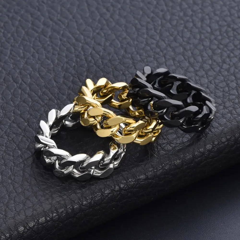 tres anillos de cadena cubana gruesos de acero titán, con acabados en plata, dorado y negro, que conforman un set de anillos de cadena cubana de acero