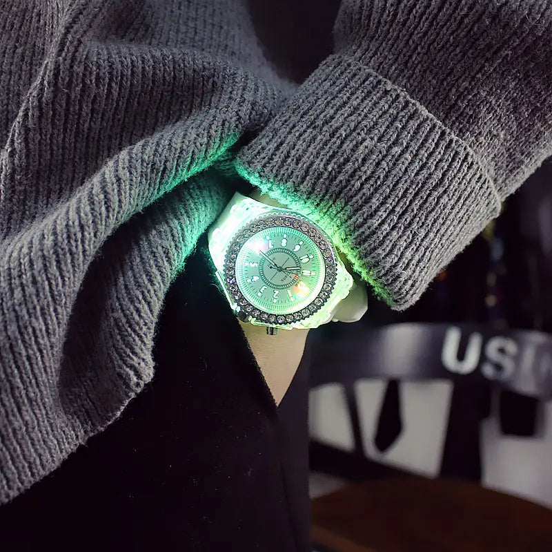 A glowing green led luminous silicone watch with a sparkling rhinestone bezel and white face worn on a wrist with a gray ribbed sweater.