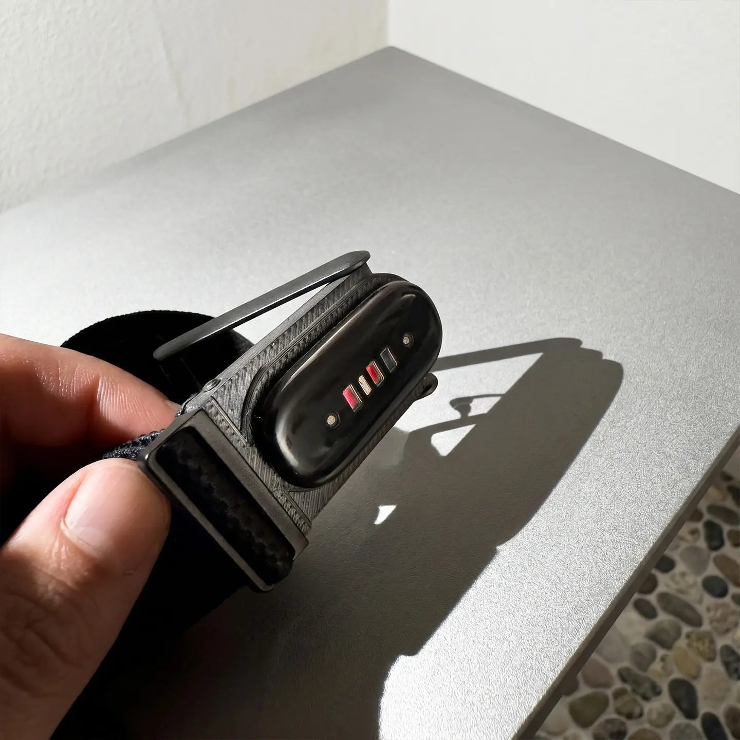 Black Xiaomi Mi Band 6 fitness tracker with a textured strap and illuminated status indicators shown with an adapter bracket frame designed for Fitbit Air to Whoop 5.0 compatibility.