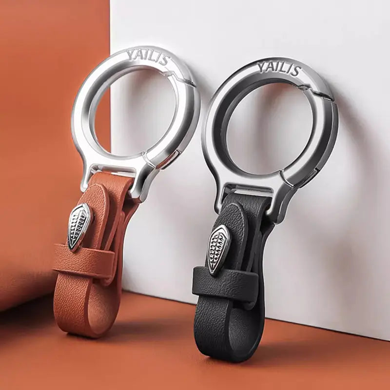 Two yailis leather car keychains with leaf charm featuring tan and black leather straps and silver-toned metal clasps and decorative leaf-shaped metallic accents.