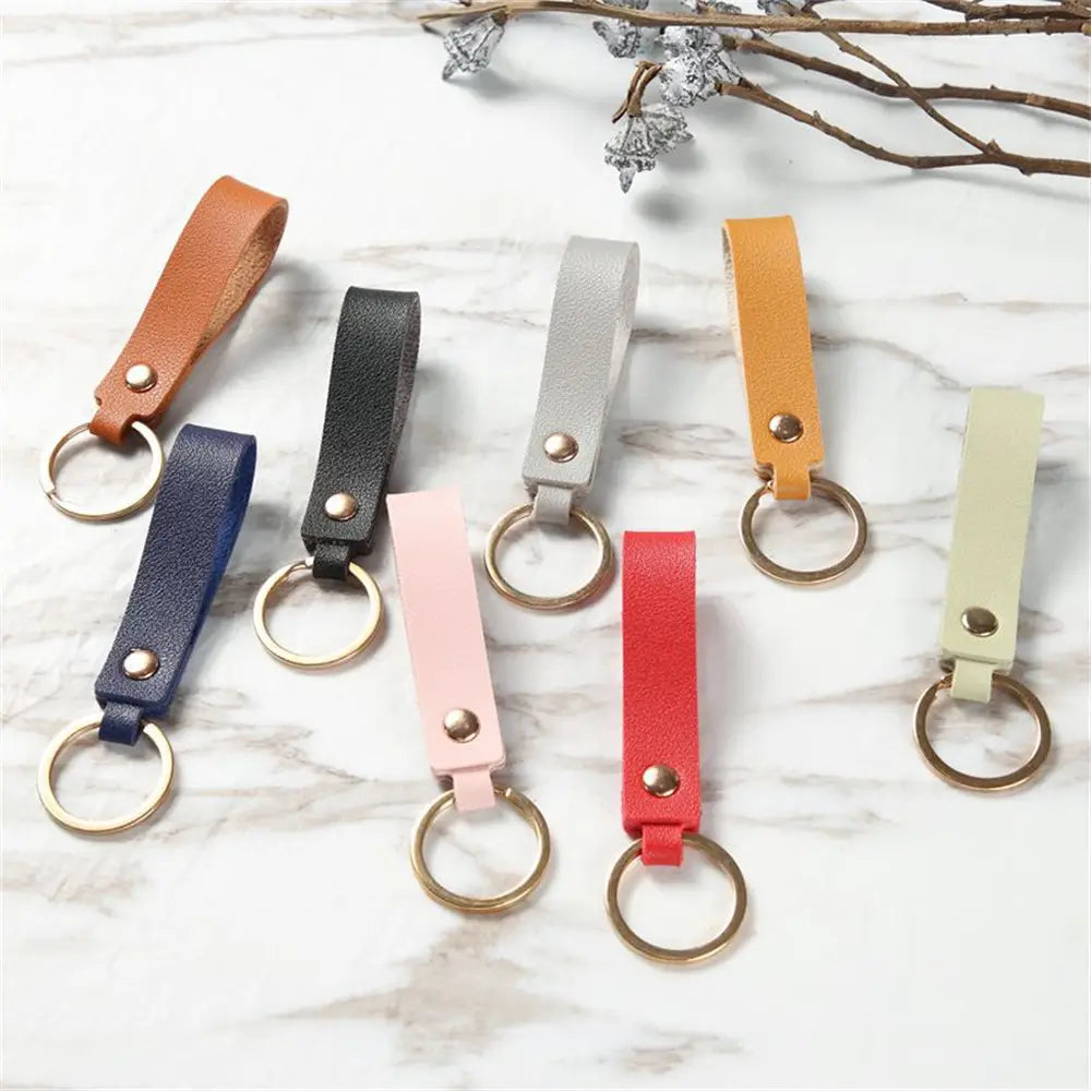 A collection of pu leather keychains featuring metal keyrings in various colors including tan black gray navy blue pink red and beige.