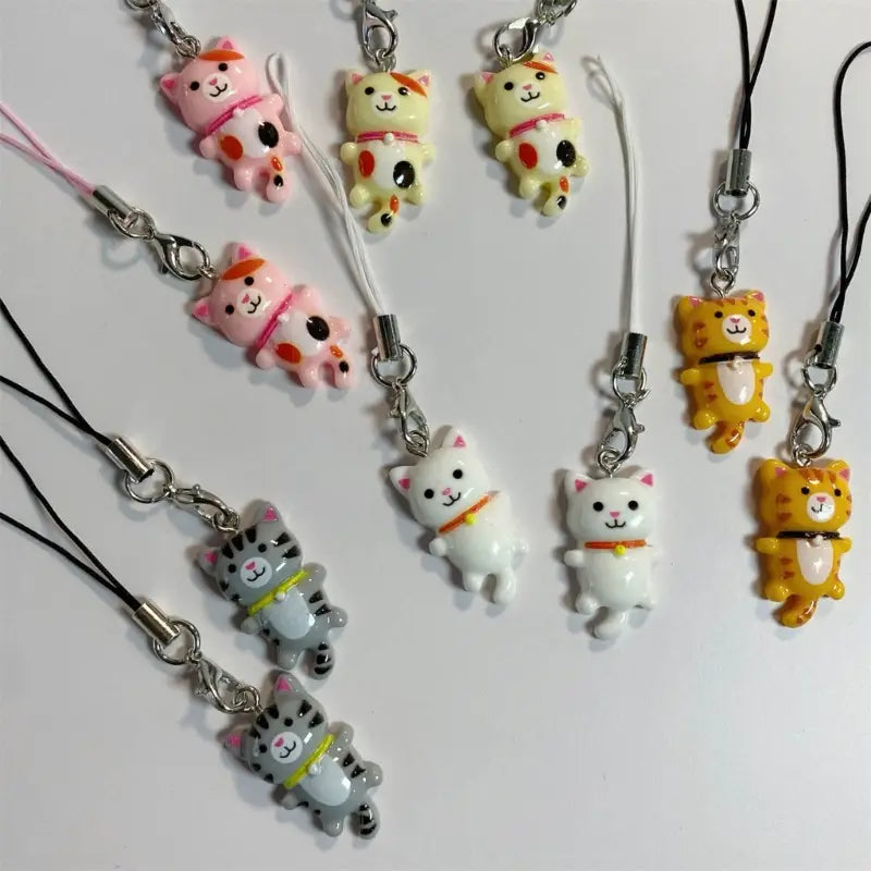 Cute cat phone charm strap featuring colorful cat-shaped keychains in pink yellow white and gray with a glossy resin finish.