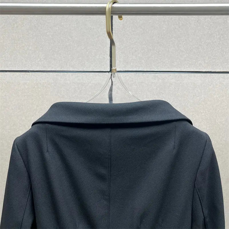 Veste blazer bleu marine foncé avec col structuré et tissage à texture subtile, associée à une jupe crayon grise taille haute de longueur genou au style Y2K.