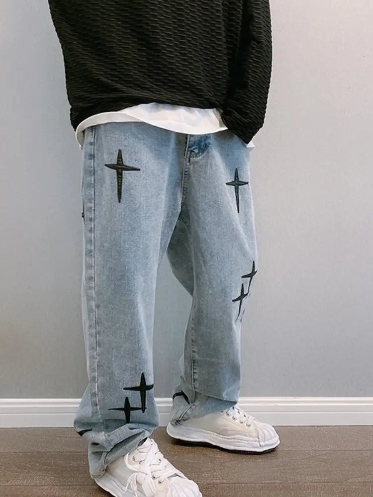 Pantalon cargo en jean à jambes larges à effet délavé clair avec broderie croisée noire sur les côtés avant et arrière.