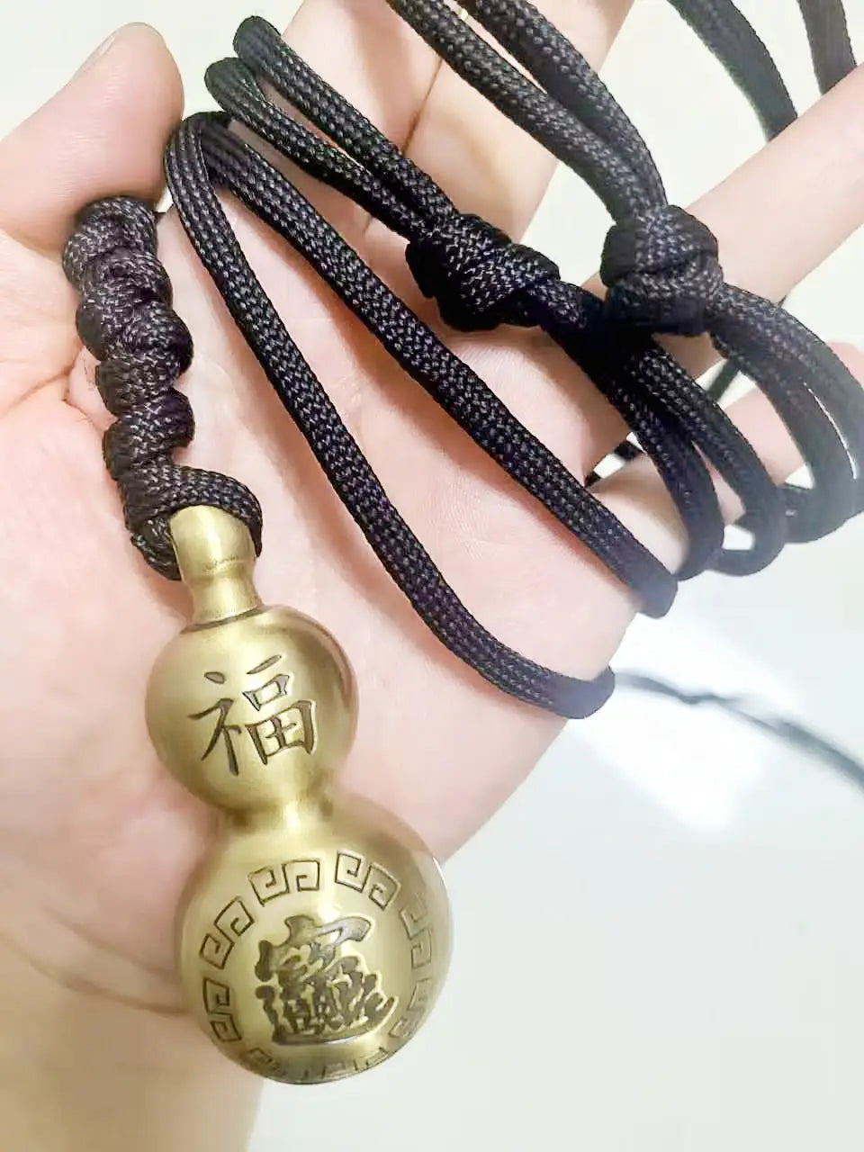 A brass-colored double-gourd shaped self defense pendant necklace with engraved Chinese characters and decorative patterns.