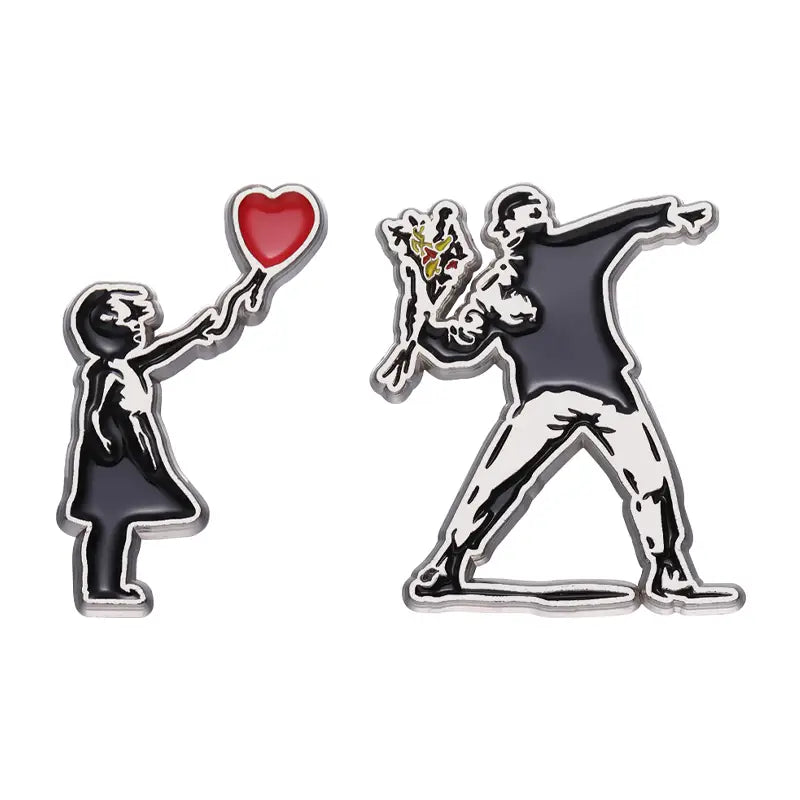 Deux épingles émaillées noires et rouges présentant des motifs d’art de rue emblématiques de Banksy : une fillette tenant un ballon en forme de cœur rouge et un homme exécutant la pose du « dab » tout en transportant des fleurs.