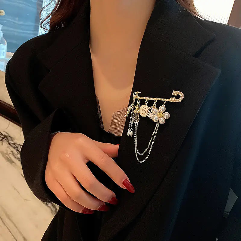 Gold-toned safety pin brooch adorned with a pearl flower charm and a number 5 pendant in the Pearl Flower Number 5 Gold Brooch Pin collection.