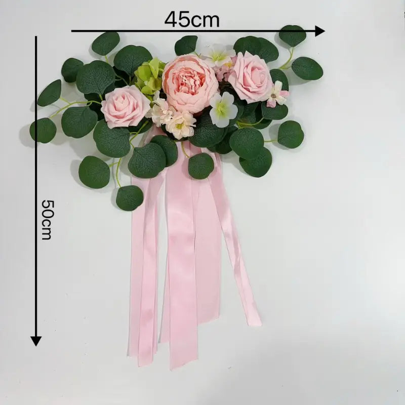Kit de décoration de voiture de mariage comprenant un délicat arrangement floral d’eucalyptus et de rose artificielle rose et blanche, rehaussé de feuilles d’eucalyptus vertes et de rubans en satin qui s’écoulent.