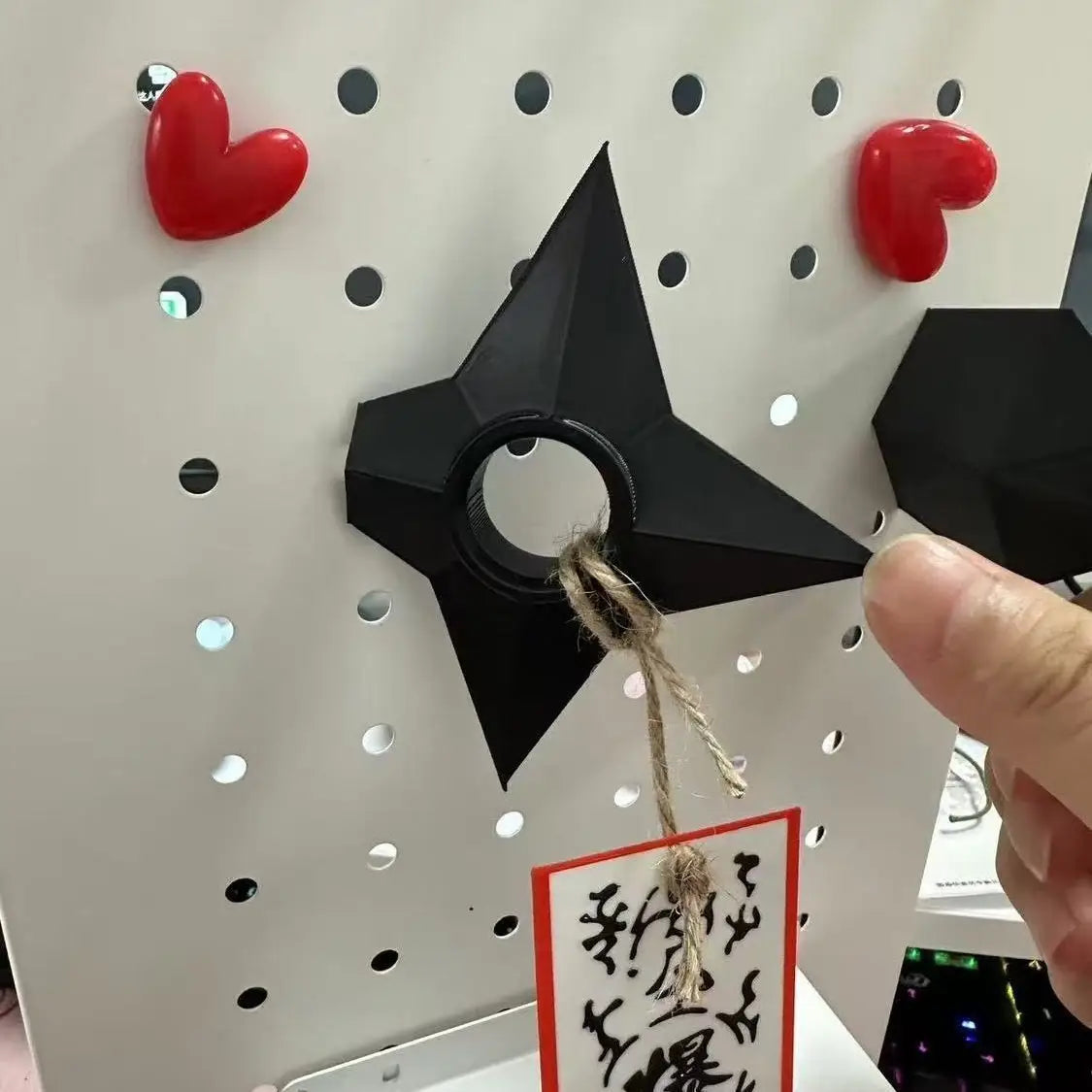 Ninja-Kunai-Shuriken-Spielzeug aus schwarzem Kunststoff aus PVC mit einem zentralen Ring und daran befestigtem Bindfaden, verwendet als Kühlschrankmagnet.