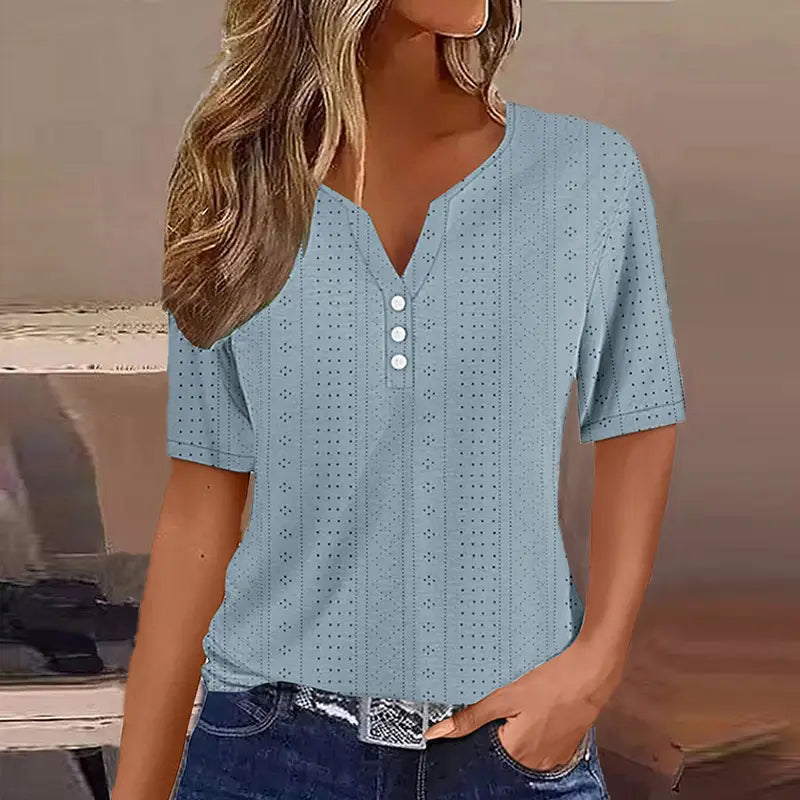 T-shirt boutonné pour femmes à encolure en V et manches courtes, de couleur bleu clair, avec un motif perforé discret et trois boutons blancs alignés sur le devant.