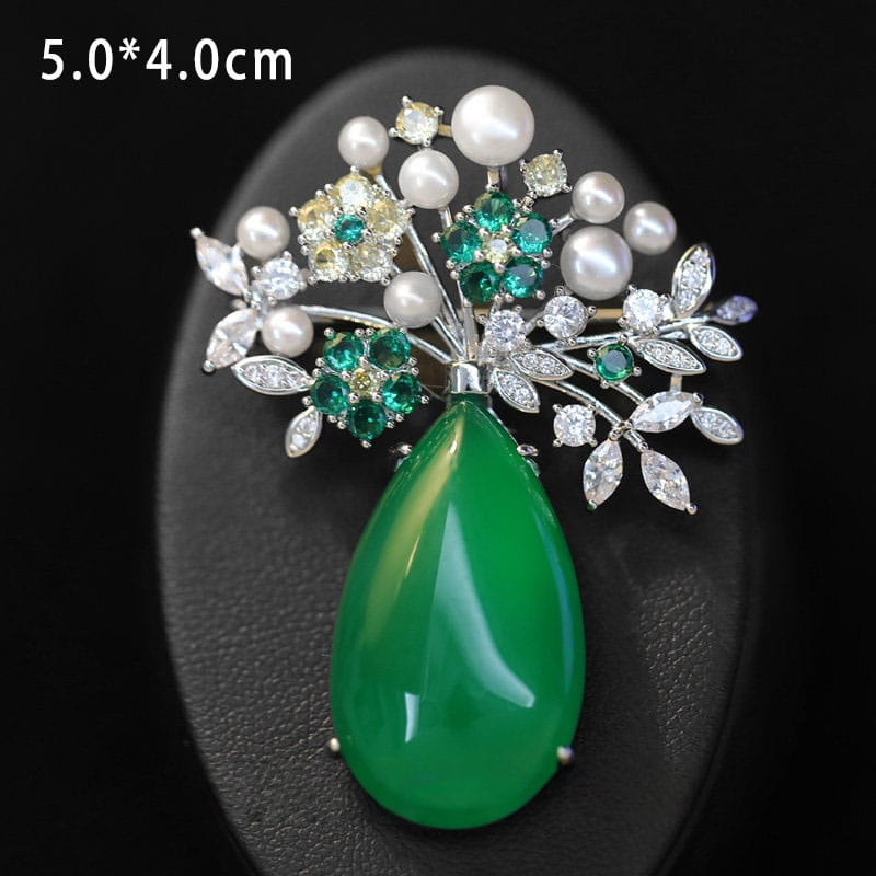 Broche de mariposa de zirconio con forma de lágrima de jade verde vibrante, pin de lujo de diseñador, adornado con perlas blancas, gemas esmeralda verde y cristales transparentes engastados en una estructura metálica de tono plateado.