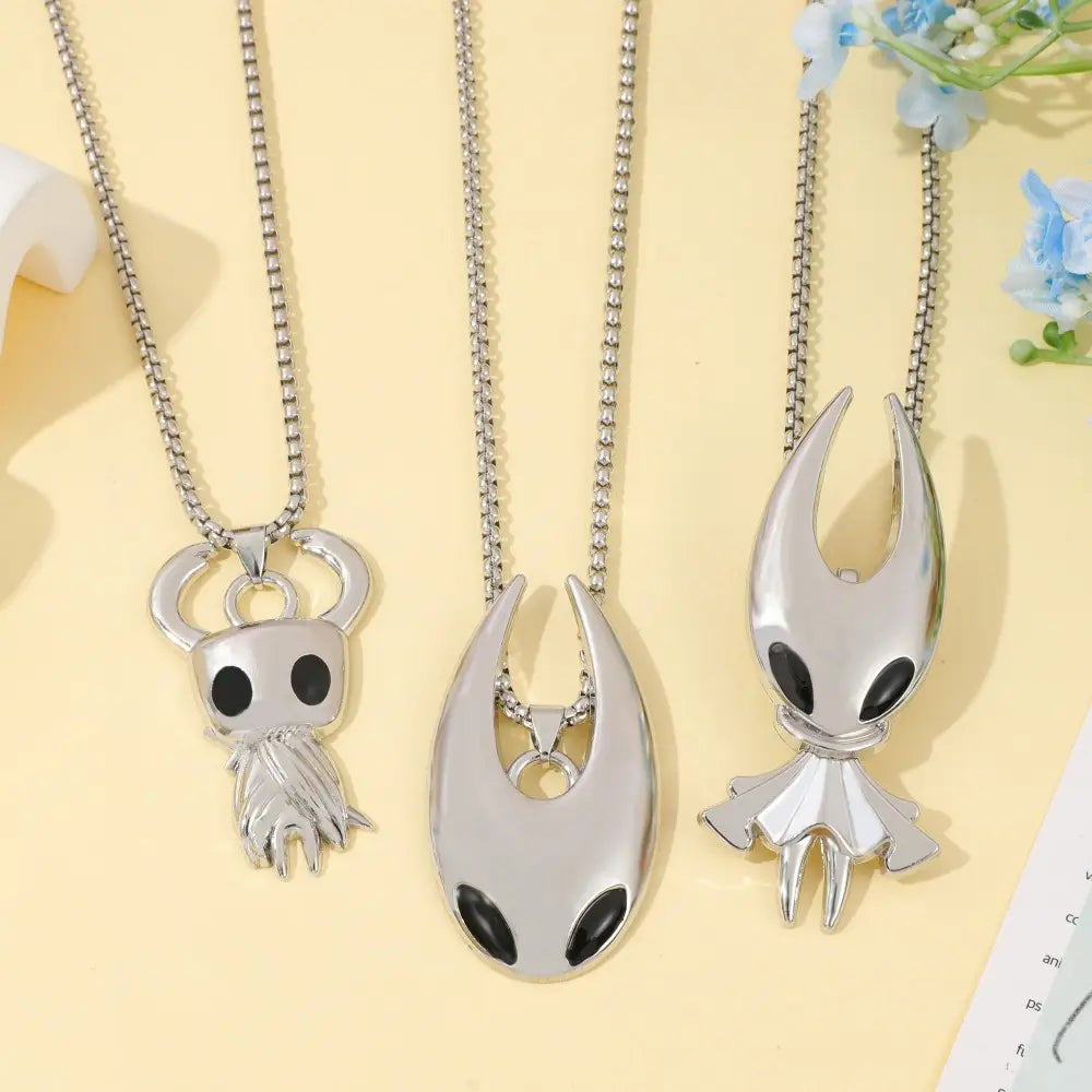 Trois colliers de jeu en pendentif argenté de chevalier creux à teinte argentée, présentant des motifs ajourés avec des accents d’yeux noirs sur des colliers à chaîne