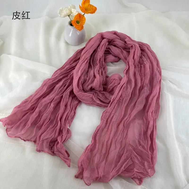 Écharpe en coton et lin plissé rose poussière doux, avec de légères ondulations et une texture fluide légère.