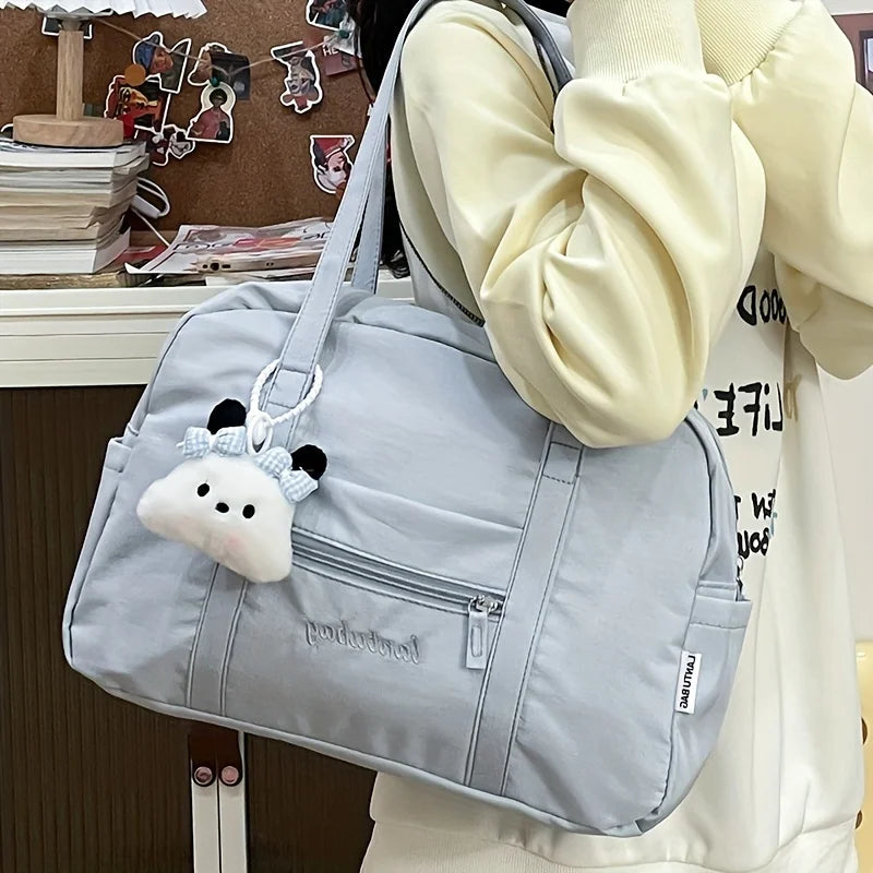 Bolsa de viaje tote de nailon acolchado duradero color gris claro con un bonito llavero de nube de peluche blanco con orejas negras y un lazo.