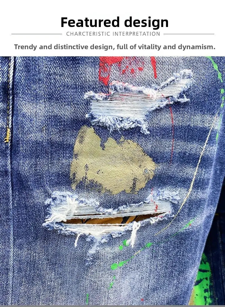 Jeans en denim déchirés peints pour hommes en denim bleu vieilli, avec des déchirures intentionnelles et des éclaboussures de peinture rouge, jaune et verte.