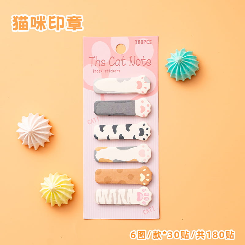 キャットメモパッド＆付箋セットの一部として、猫ノートのブランド表記が施されたピンクのカードに梱包された、さまざまなパステルカラーと柄の猫の肉球型インデックスシール180枚セット。