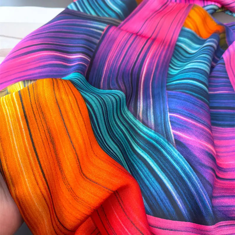 Ein lebendiger Seidenschal für Damen mit kräftigen wellenförmigen Streifen in leuchtenden Farben, darunter Pink, Orange, Petrol und Lila, entworfen als Colorblock-Frühlingsschal-Wickel.
