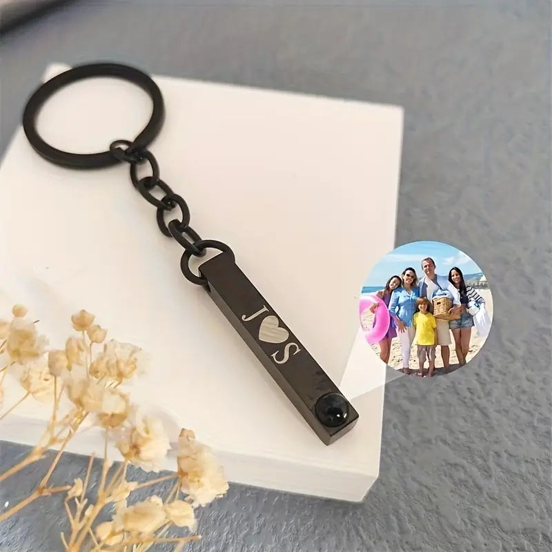 Black metal custom photo projection keychain featuring an engraved j heart s and a small black gemstone at the end.