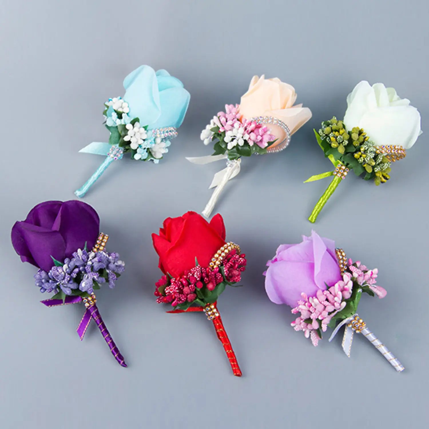 A collection of artificial silk rose boutonnieres in assorted vibrant colors with delicate floral accents and jeweled embellishments for wedding corsages.