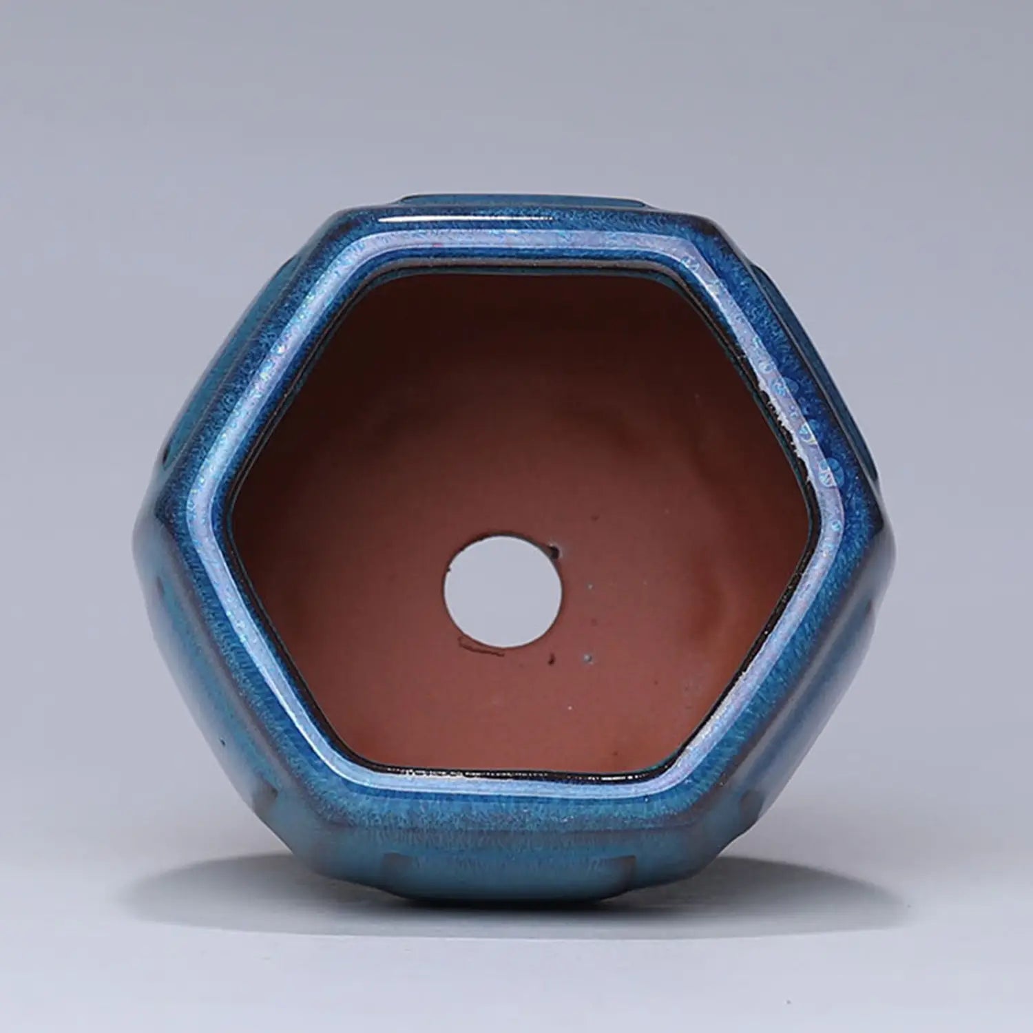 Sechseckiger Keramik-Blumentopf mit glänzender blauer Rippenglasur und Terrakotta-Innenraum, mit zentralem Drainageloch für ein gesundes Pflanzenwachstum.
