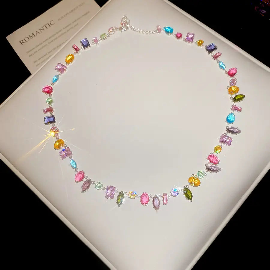 A vibrant colorful zircon crystal gold plated necklace with a silver chain featuring multi-colored faceted stones in pink blue yellow green purple and orange.
