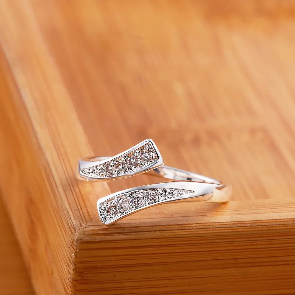 Verstellbarer Zirkonring aus 18k Gold in Silber für Damen mit einem eleganten, modernen Design: zwei geschwungene Bänder, verziert mit funkelnden, klaren kubischen Zirkonia-Steinen in einer polierten, metallischen Ausführung.