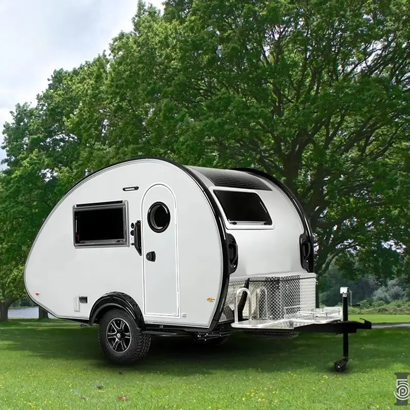 White teardrop travel trailer with black accents and a sleek rounded design fully equipped for camping.