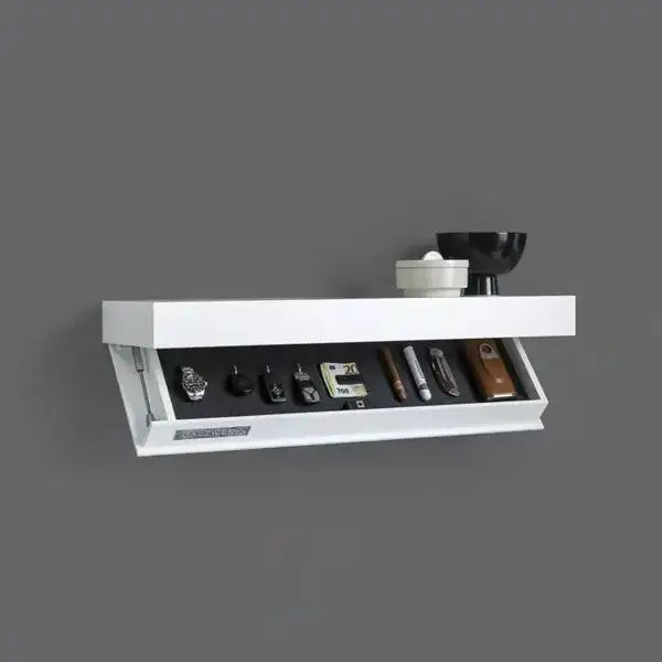 Étagères flottantes blanches fixées au mur avec un design moderne épuré, comprenant un tiroir à compartiment dissimulé et ouvert permettant de ranger des montres et de petits outils.