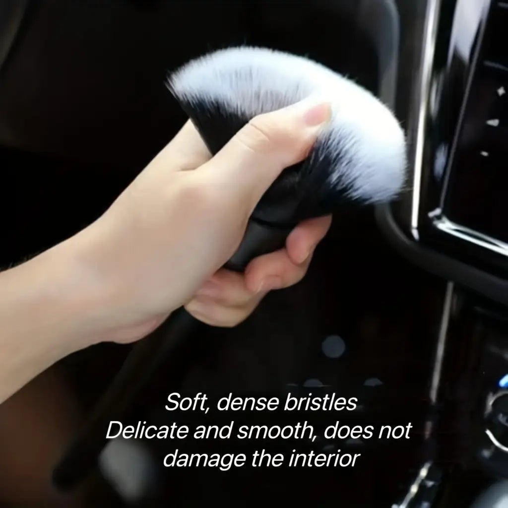Bürste zur Detailreinigung im Innenraum eines Fahrzeugs mit schwarzem Griff, weichen Borsten und dichten weißen Borsten zur schonenden Reinigung.