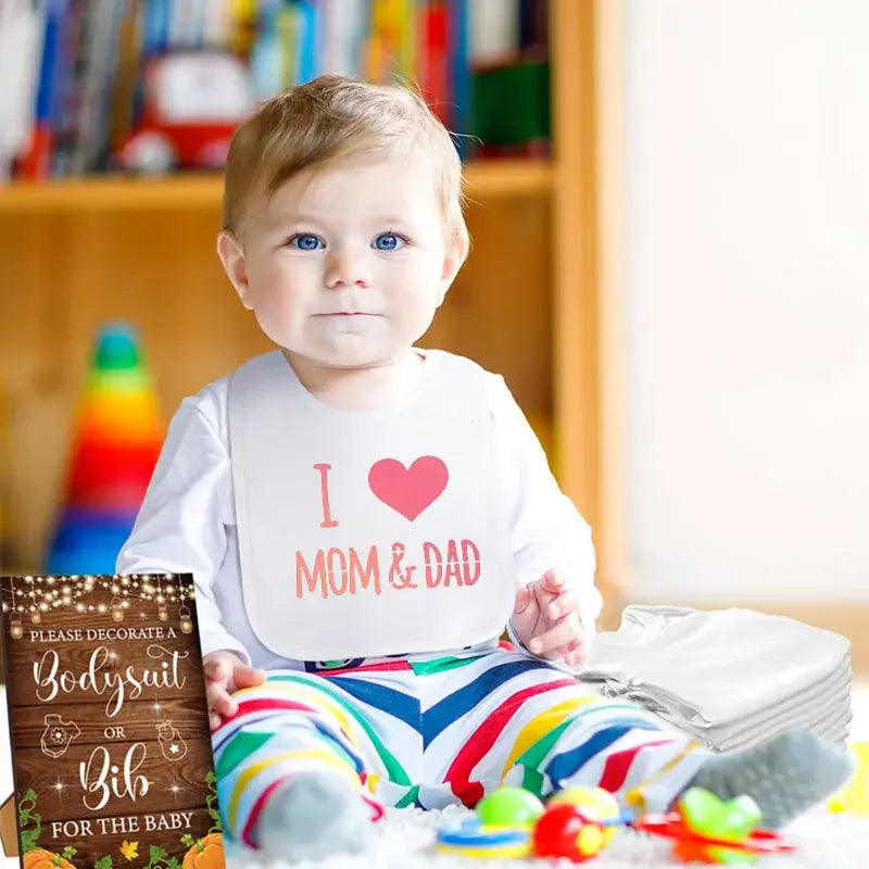 White baby bib with pink i heart mom and dad text and heart design from diy baby shower bib and bodysuit decorating kit worn by a baby.