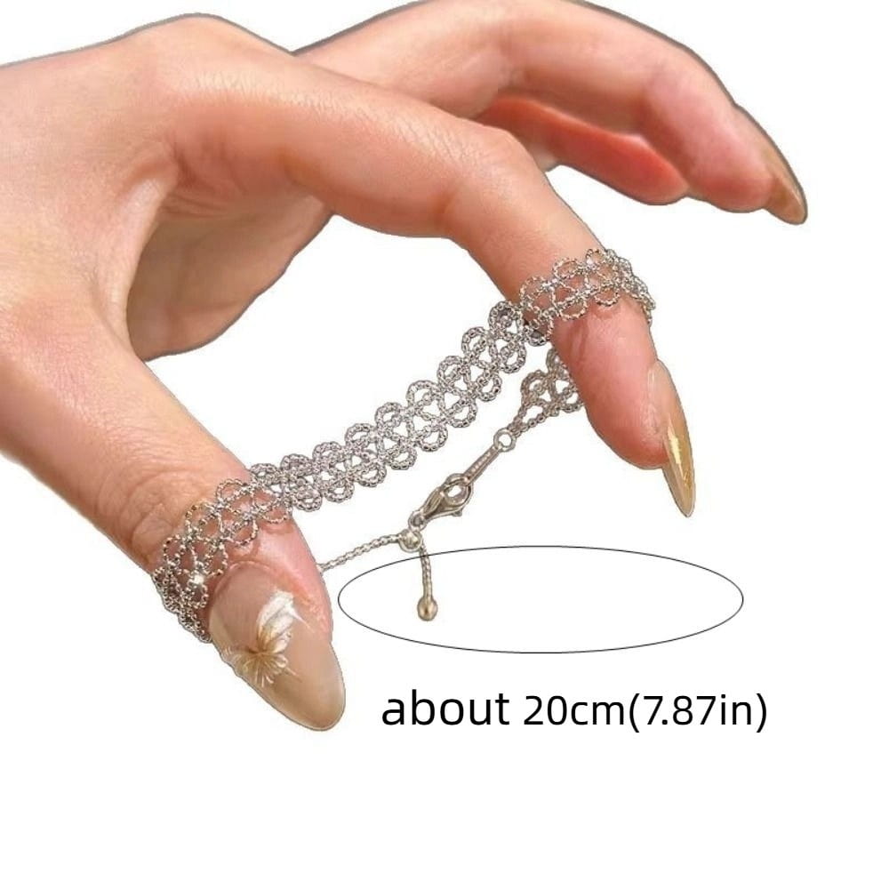 Silver metal lace bracelet featuring an adjustable chain finger ring with intricate lace-like design and small dangling charm.