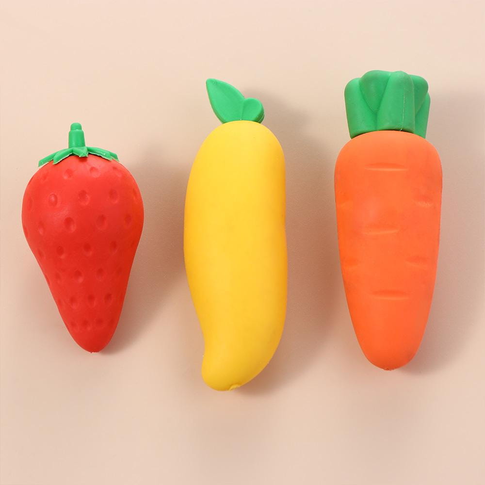 three colorful fruit pencil erasers shaped like a red strawberry with green leaves, a yellow banana with a small green leaf, and an orange carrot with a textured green crown in a cute student stationery set