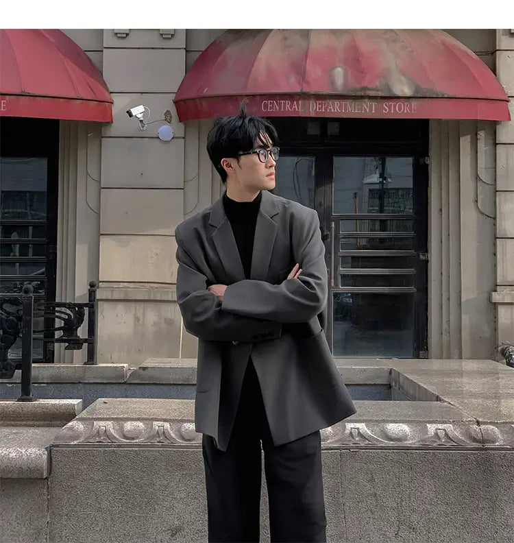 Un hombre que lleva una blazer de doble botonadura oversize casual para hombre en poliéster gris oscuro, con un ajuste estructurado pero relajado.