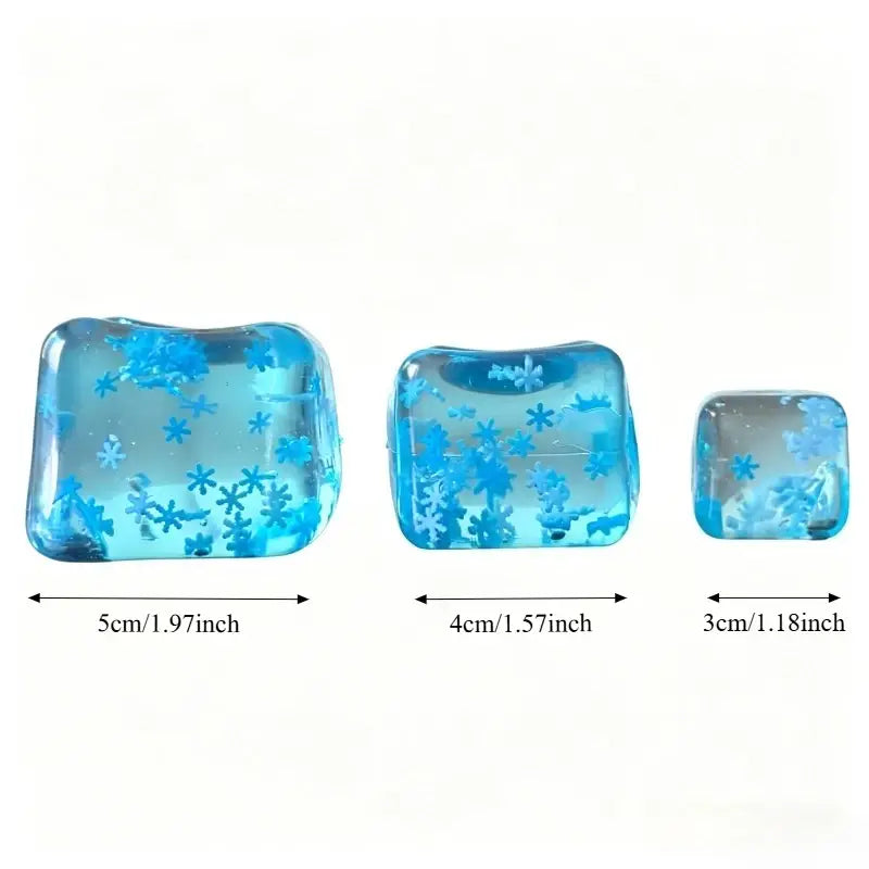 drei durchscheinende blaue Harz-Eiswürfel Stressabbau-Spielzeugwürfel mit eingebetteten Schneeflocken-Designs in unterschiedlichen Größen, von vorne betrachtet