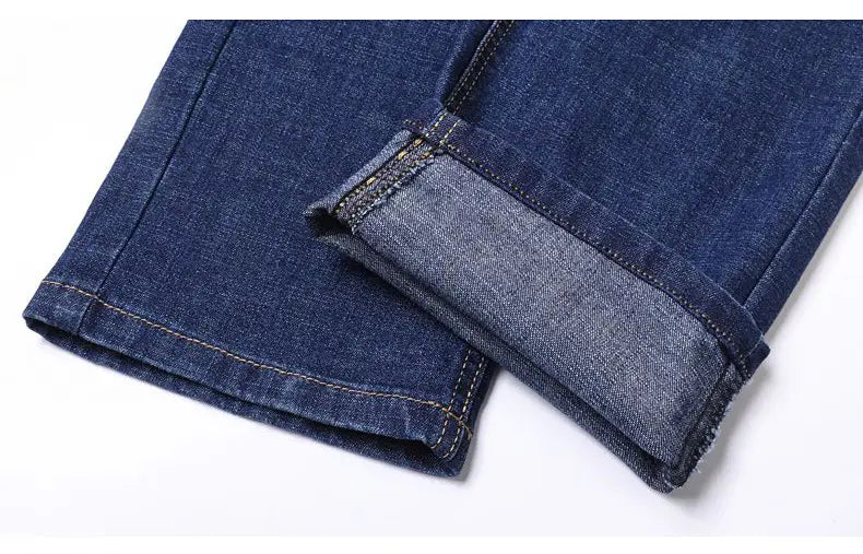 Men’s dark blue stretch cotton straight jeans with rolled-up cuffs showing lighter inner lining and contrasting stitching for casual wear