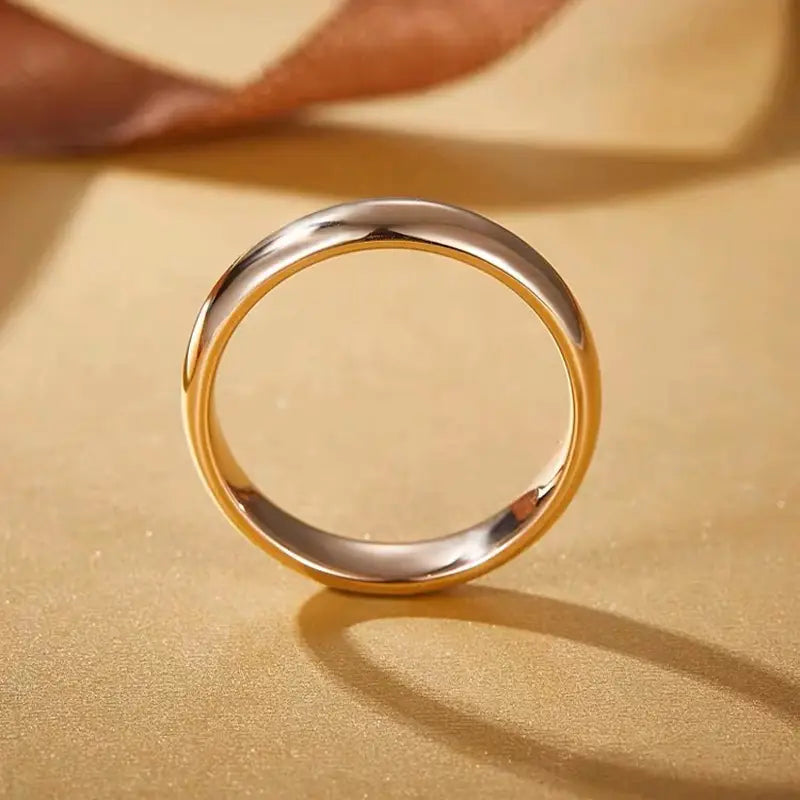 Un anillo de pareja de argollas de boda de oro de 18 quilates y 4 mm con acabado pulido, que presenta una superficie exterior plateada pulida y un revestimiento interior cálido en oro.