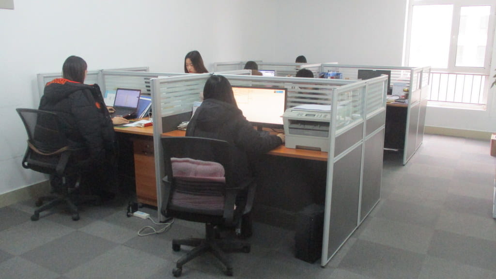 gray office cubicle with white partition panels and wooden desk surface shown alongside a 3-station multi-function home gym equipment for versatile workout use