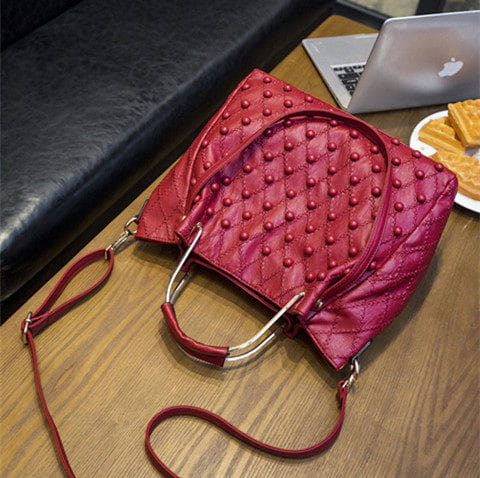 Bolso de hombro de cuero rojo con diseño acolchado, asas de metal de tono plateado y compartimento interior con una correa desmontable a juego.