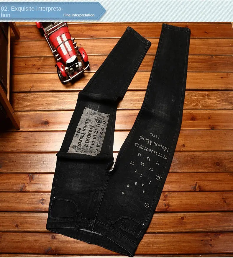 Mens slim fit printed black denim jeans with a distressed faded look and white numerical and text embroidery on the leg.