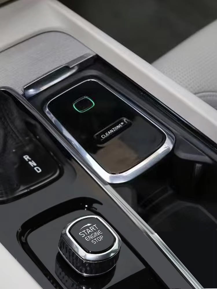 Black and silver Cleanzone button with a glowing green square indicator framed in chrome on the Volvo Cleanzone wireless car charger and air purifier.