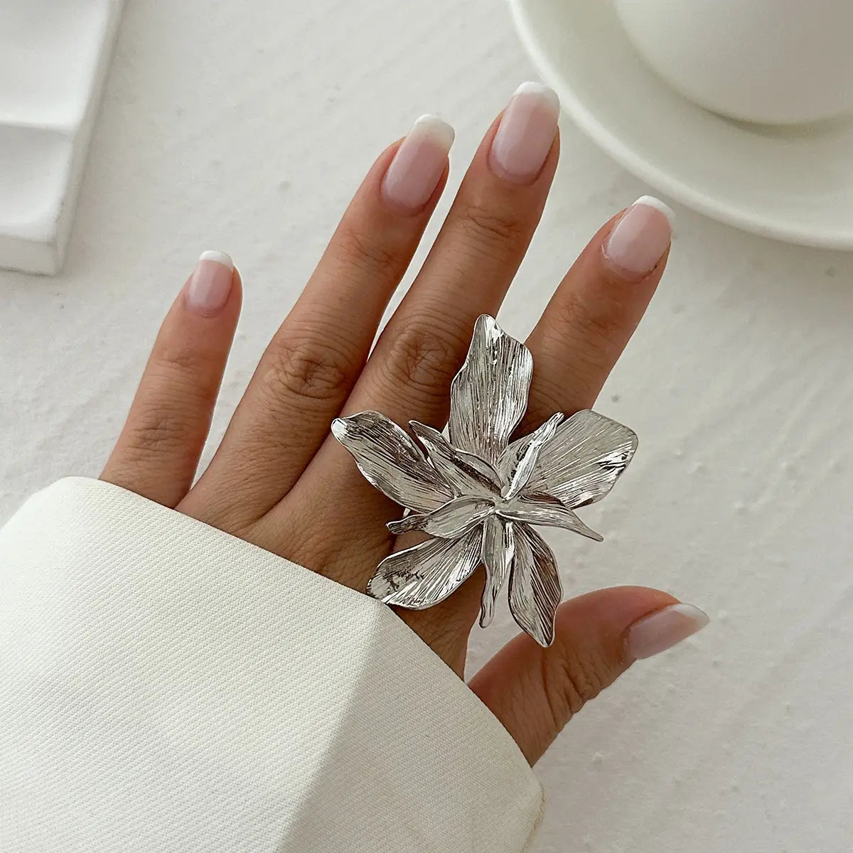 Adjustable double layer flower ring made of silver featuring intricately designed textured petals.
