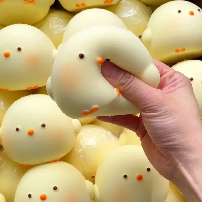 Un juguete blando tipo gallina gigante de color amarillo pálido y suave con ojos negros diminutos y un pico naranja, para aliviar el estrés.