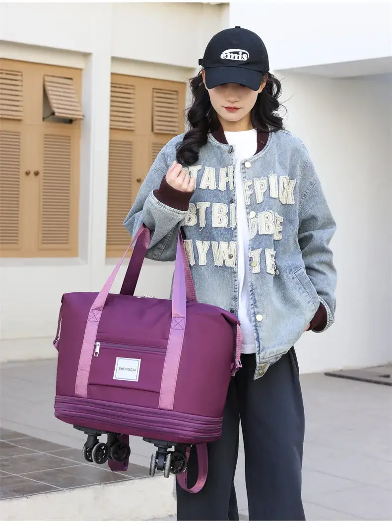 Un sac duffel roulant violet à grande capacité, avec des poignées roses et une étiquette blanche à l’avant, conçu comme sac à dos de voyage pour un transport pratique