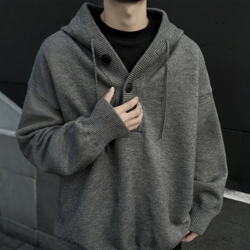 Herren-übergroßer Strickpullover mit Kapuze im Stil eines Retro-Streetwear-Pullovers mit grauem Strickstoff sowie schwarzen Knöpfen und Kordelzügen.