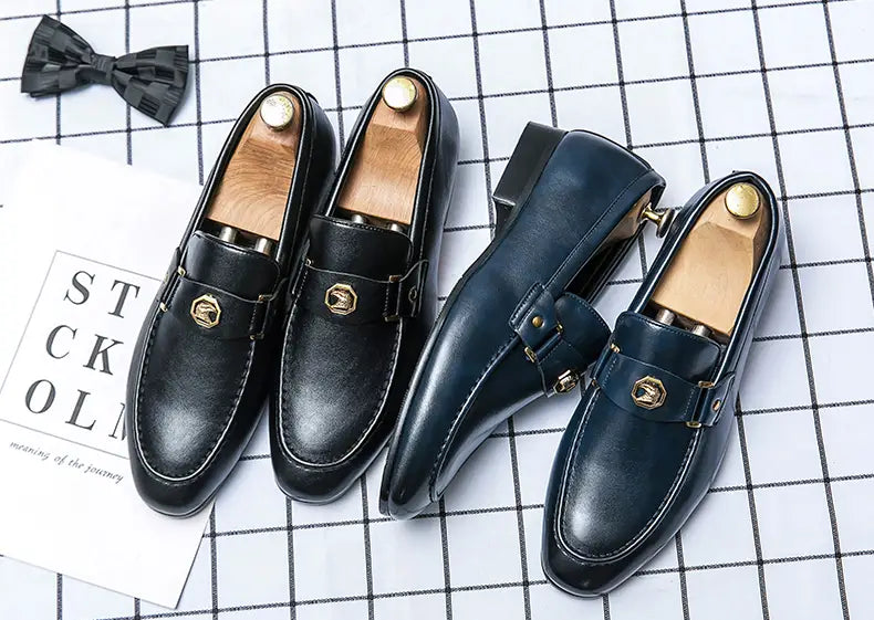 Ein Paar Herren-Lederslipper im eleganten Stil in Schwarz mit goldfarbenen sechseckigen Schnallen und Holz-Einlagen.